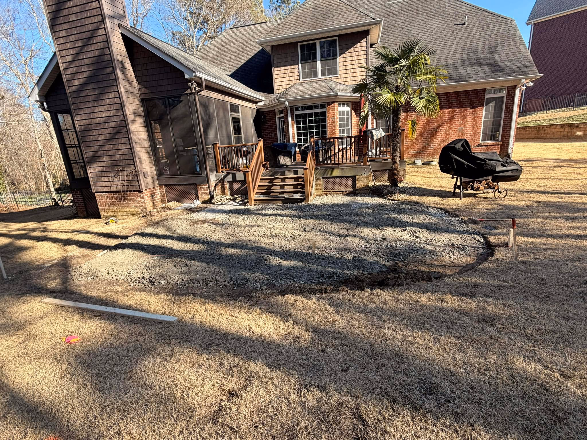 Backyard behind a house covered in loose gravel and bare dirt before the patio was built.