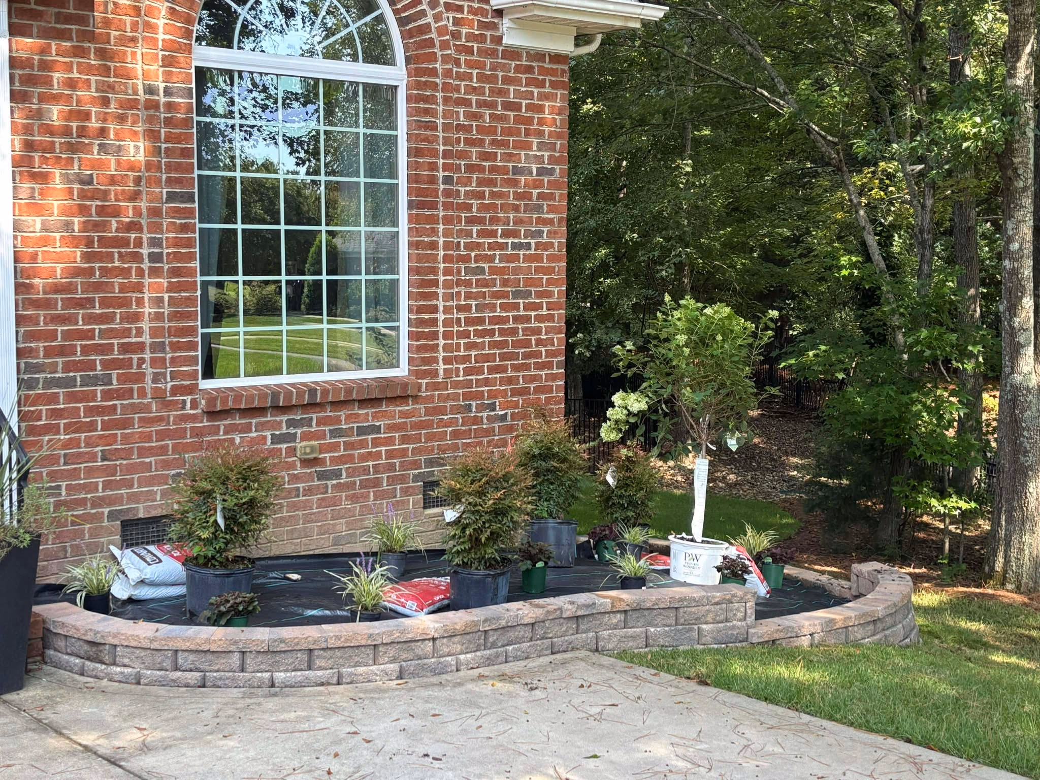 Planted foundation bed with a stone border beside a brick home.