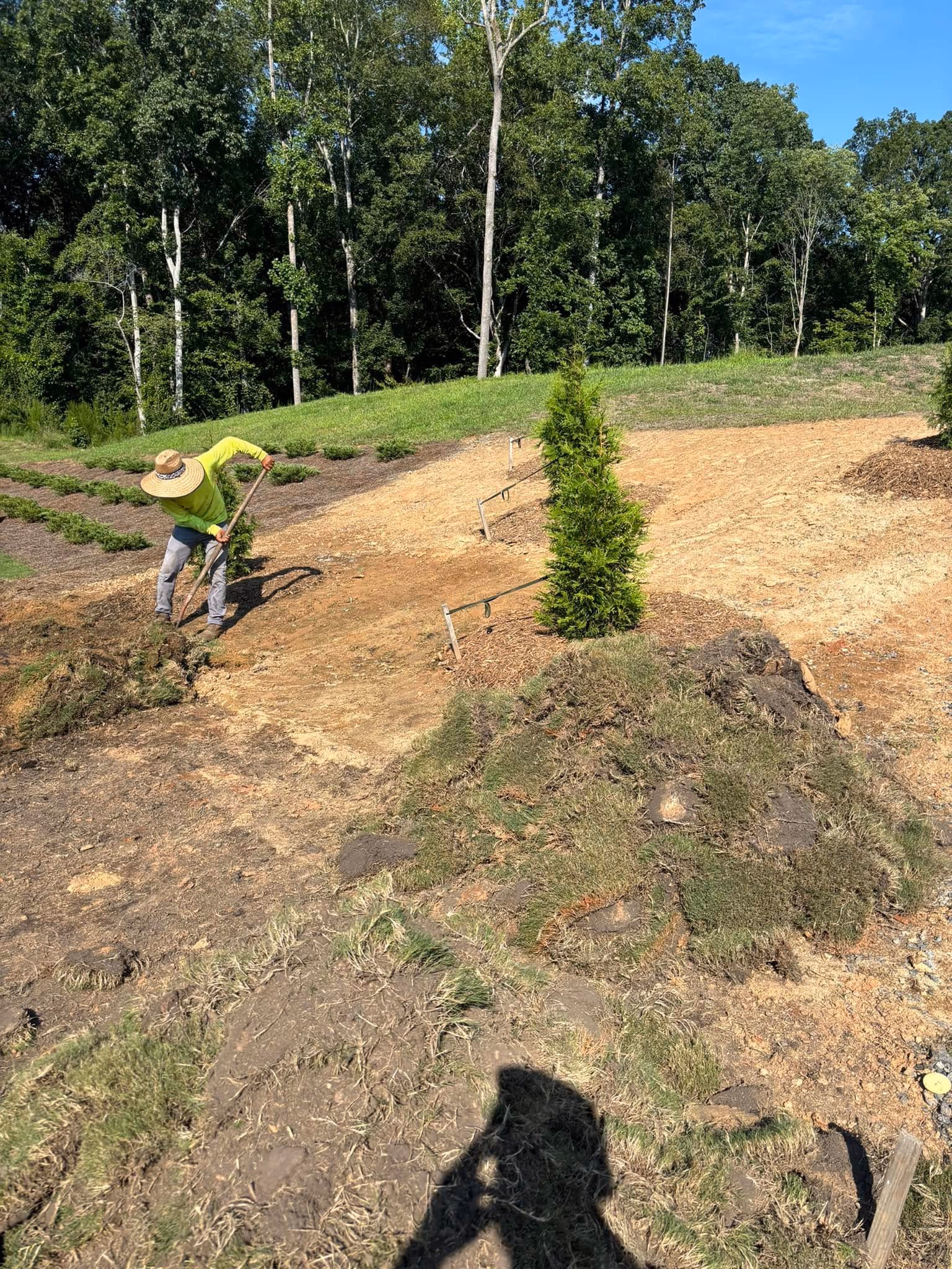 Excavated slope being cut and shaped during a grading job beside a residential yard.