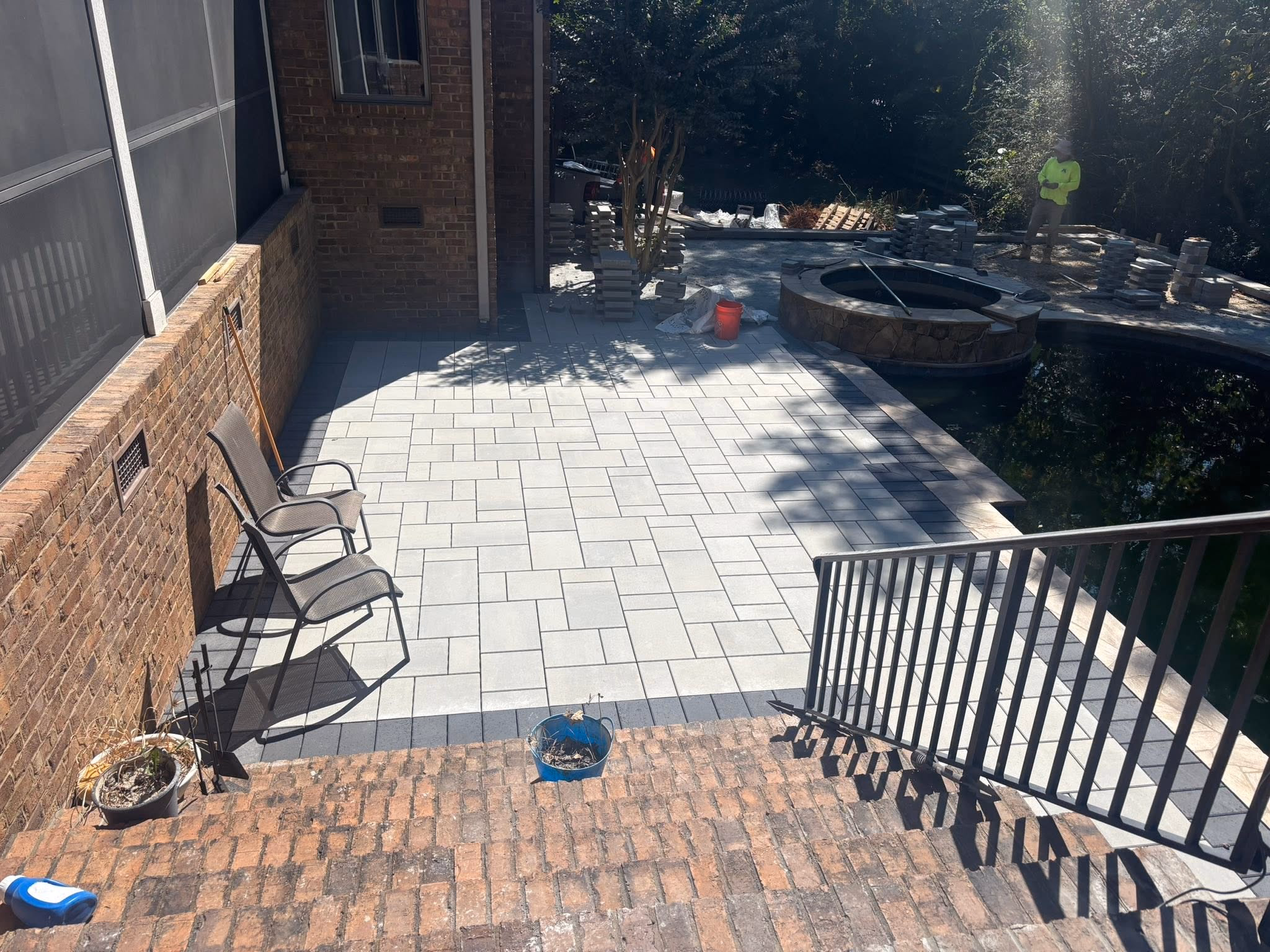 Finished paver patio with a fire pit and outdoor seating beside a brick home.