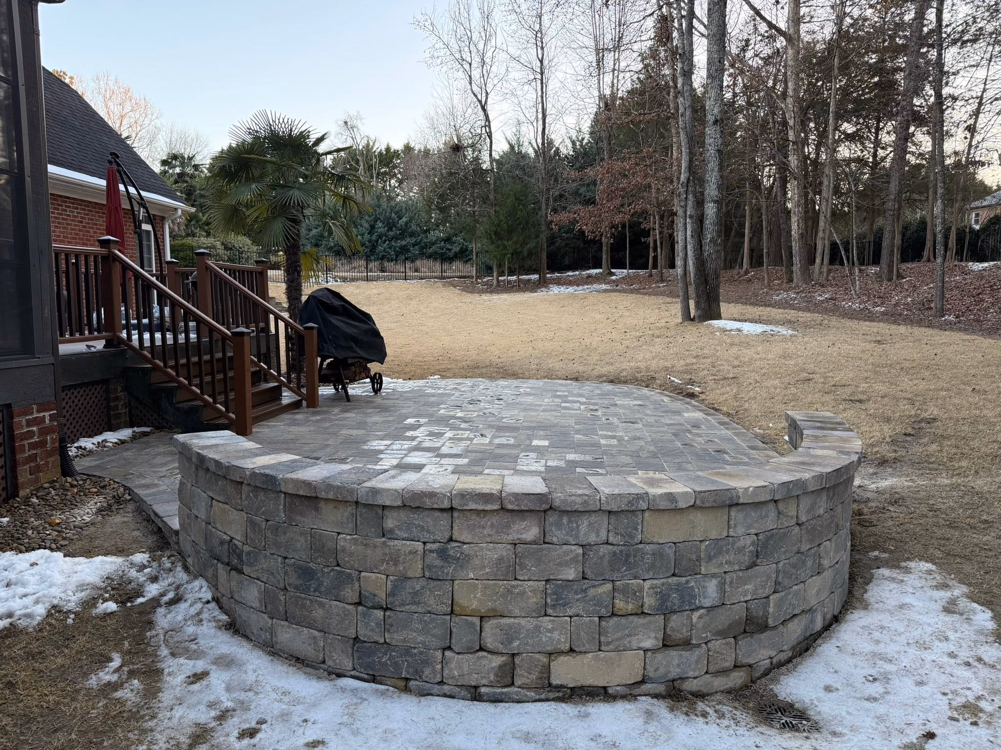 Fire pit wall built up course by course on a prepared base beside a deck.