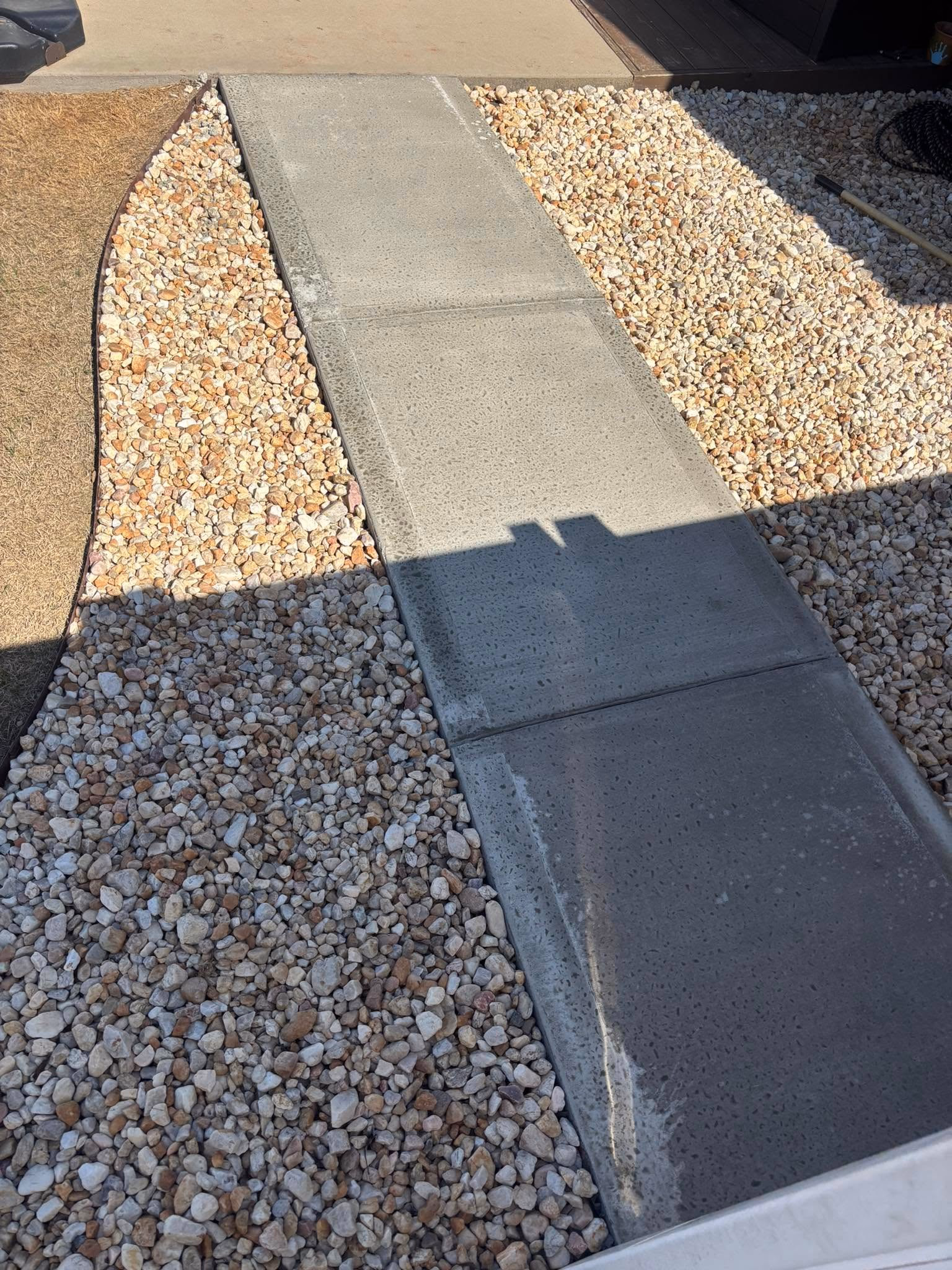 Concrete walkway with a gravel border running alongside a home.