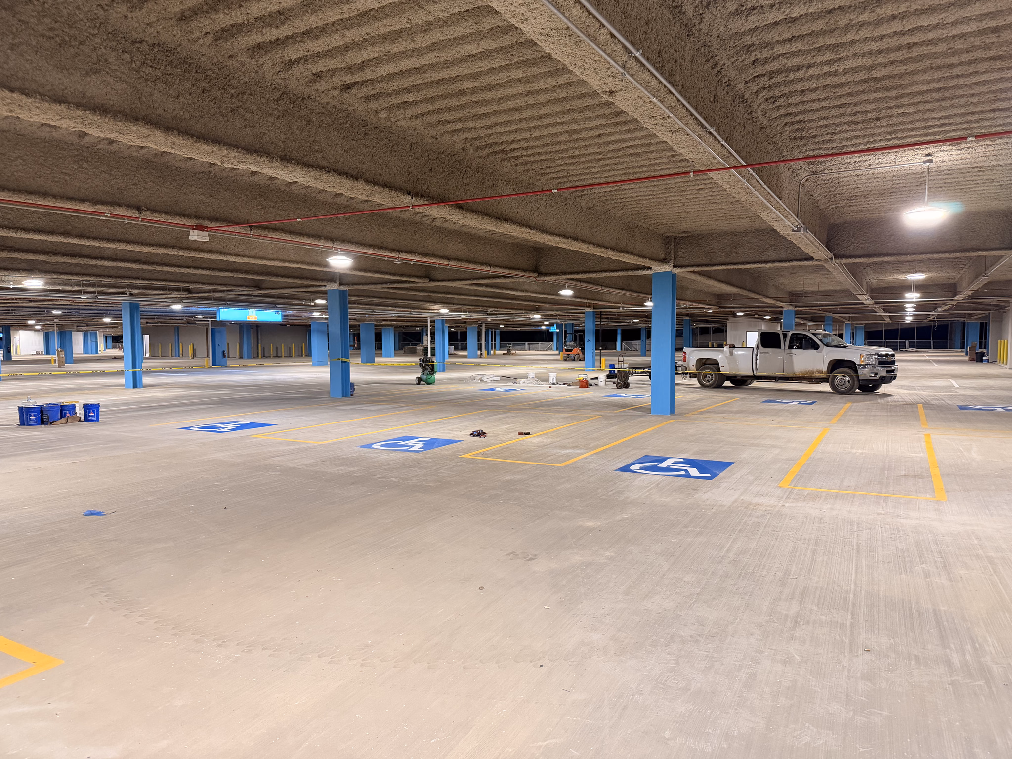 Completed parking deck level with fresh white stall lines and blue accessible spaces.