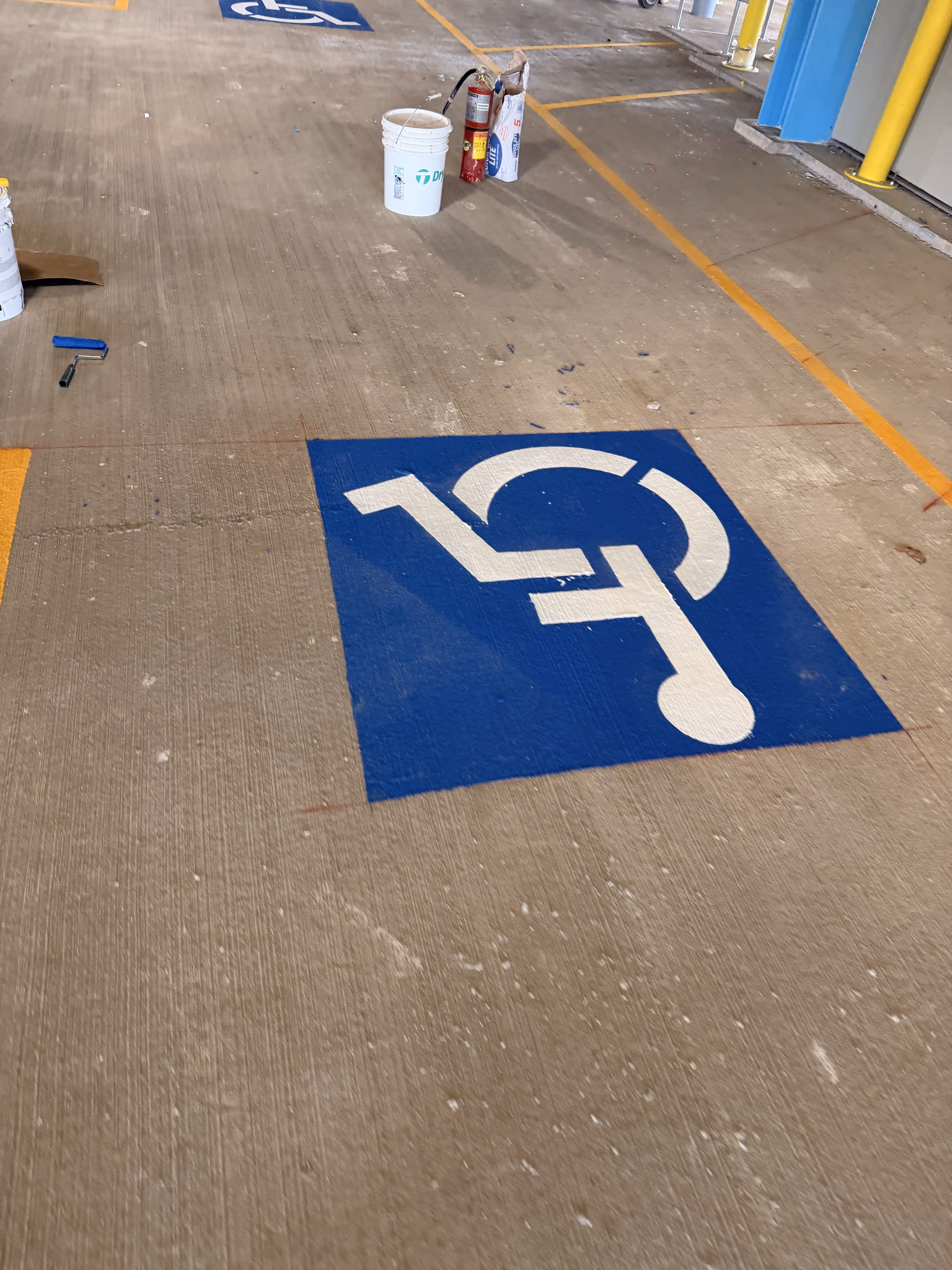 Freshly painted blue and white accessible parking symbol on a concrete parking surface.